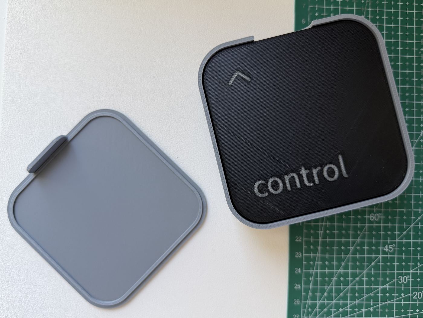 Our print from above: the holder open with the control coaster on top of the stack, and the cap beside it showing its plug and tab.